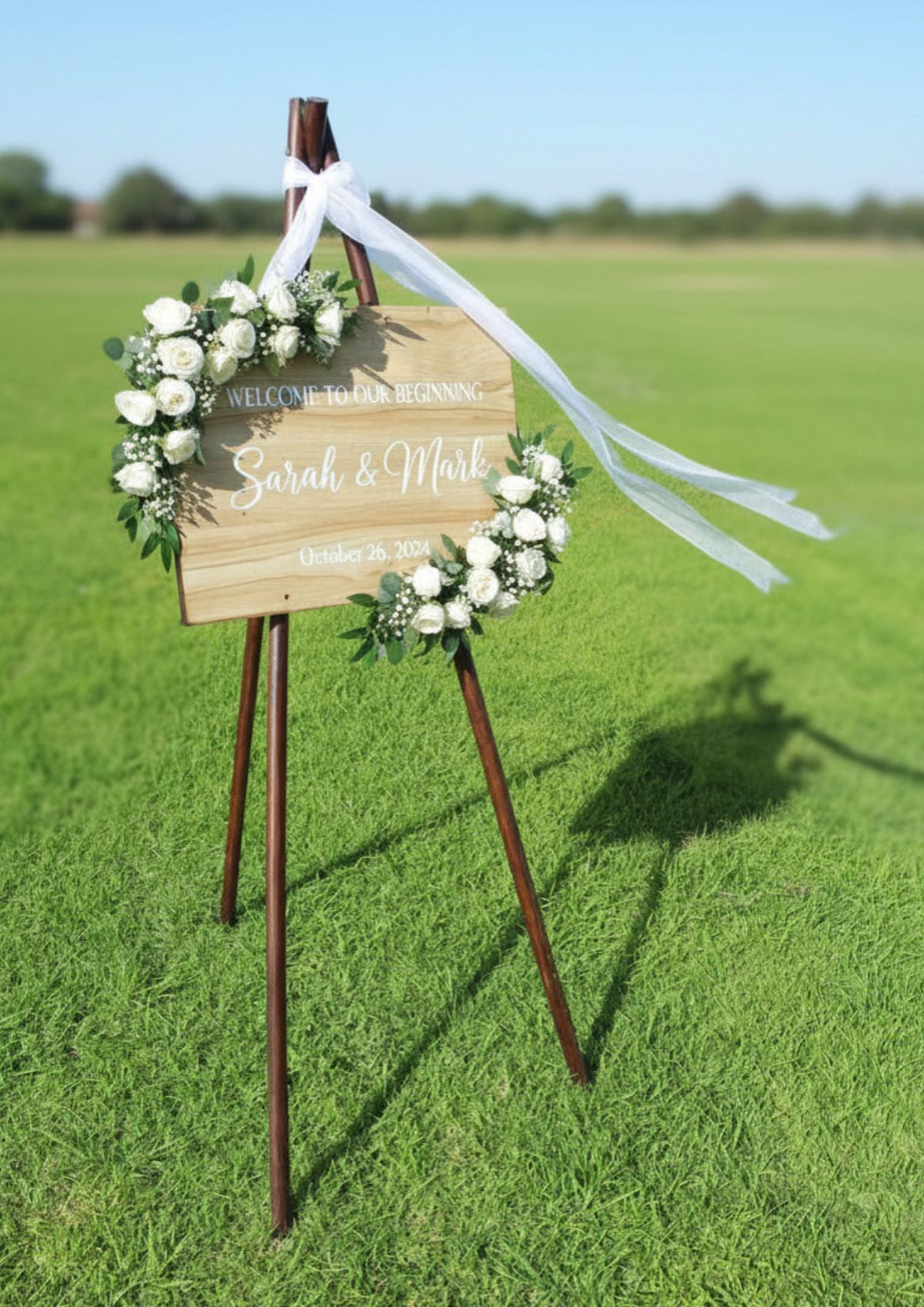 Welcome sign with white roses in an open field
